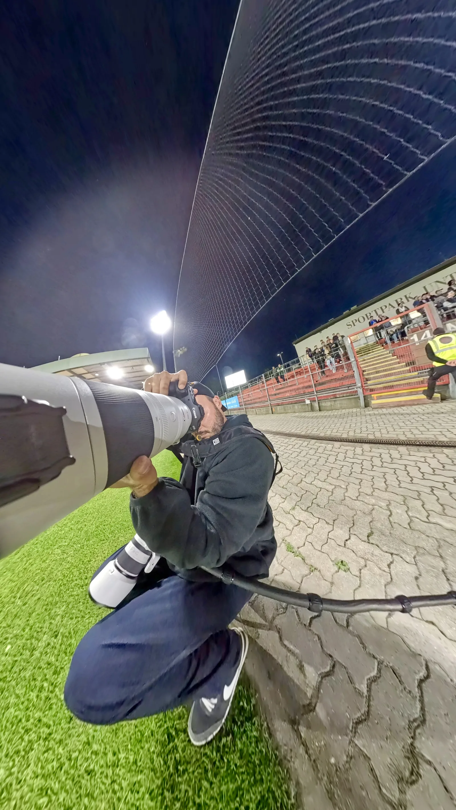 Sportfotograf Max Kolleritsch mit Kamera und Teleobjektiv am Spielfeldrand im Sportpark Unterhaching