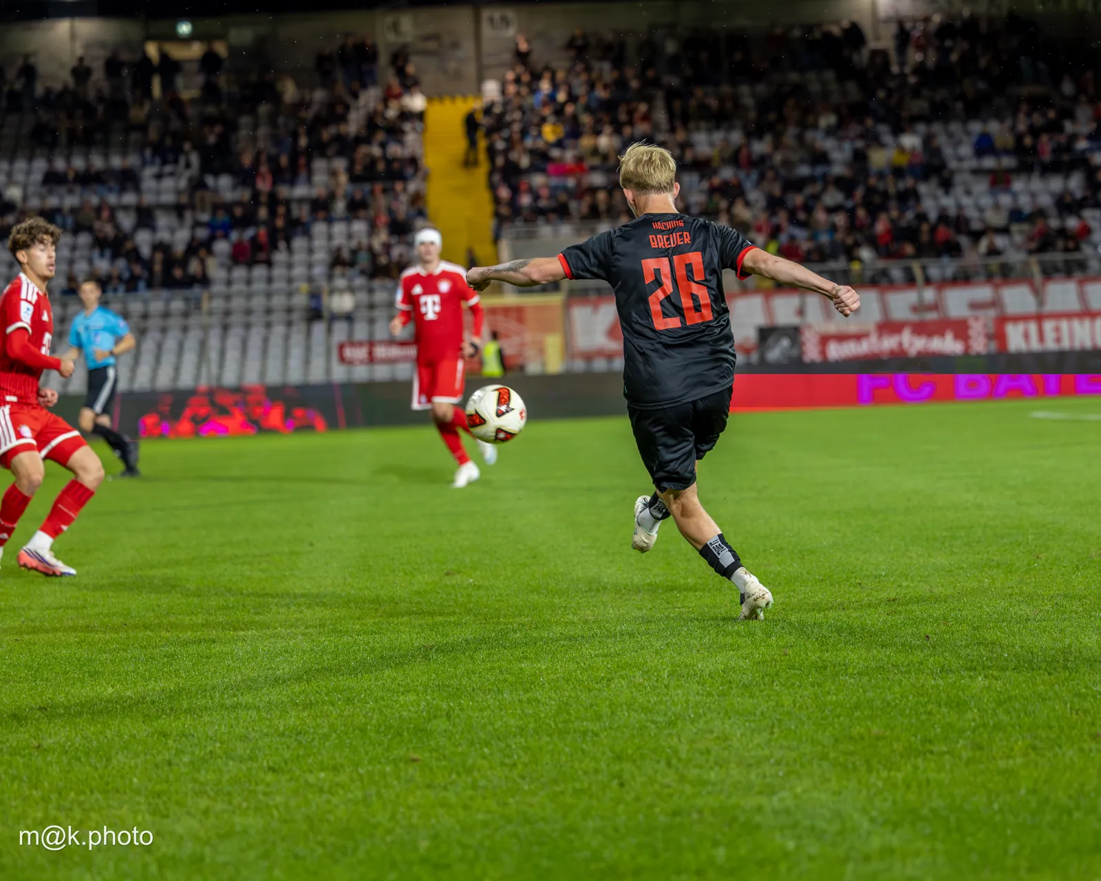 SpVgg Unterhaching player in a black kit playing the ball against FC Bayern Munich